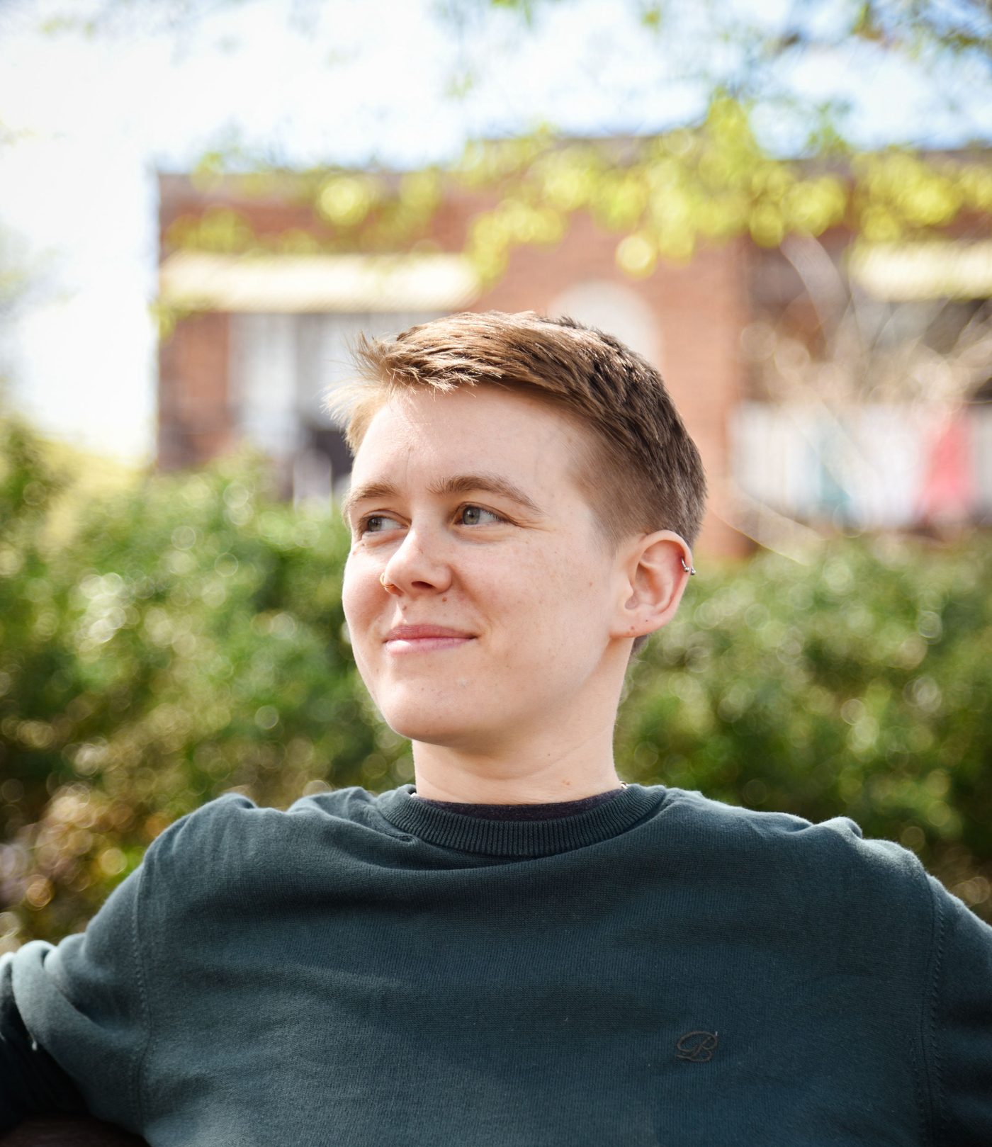 Filip outdoors in front of greenery, looking away from the camera.