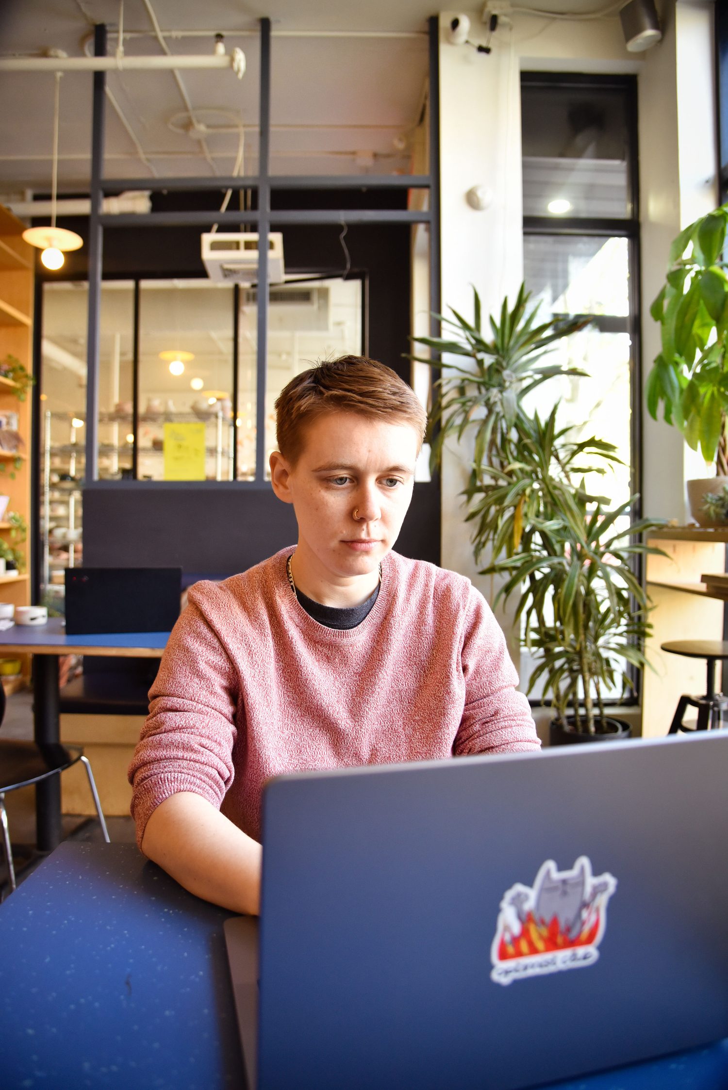Filip working on a laptop at a café table surrounded by plants.