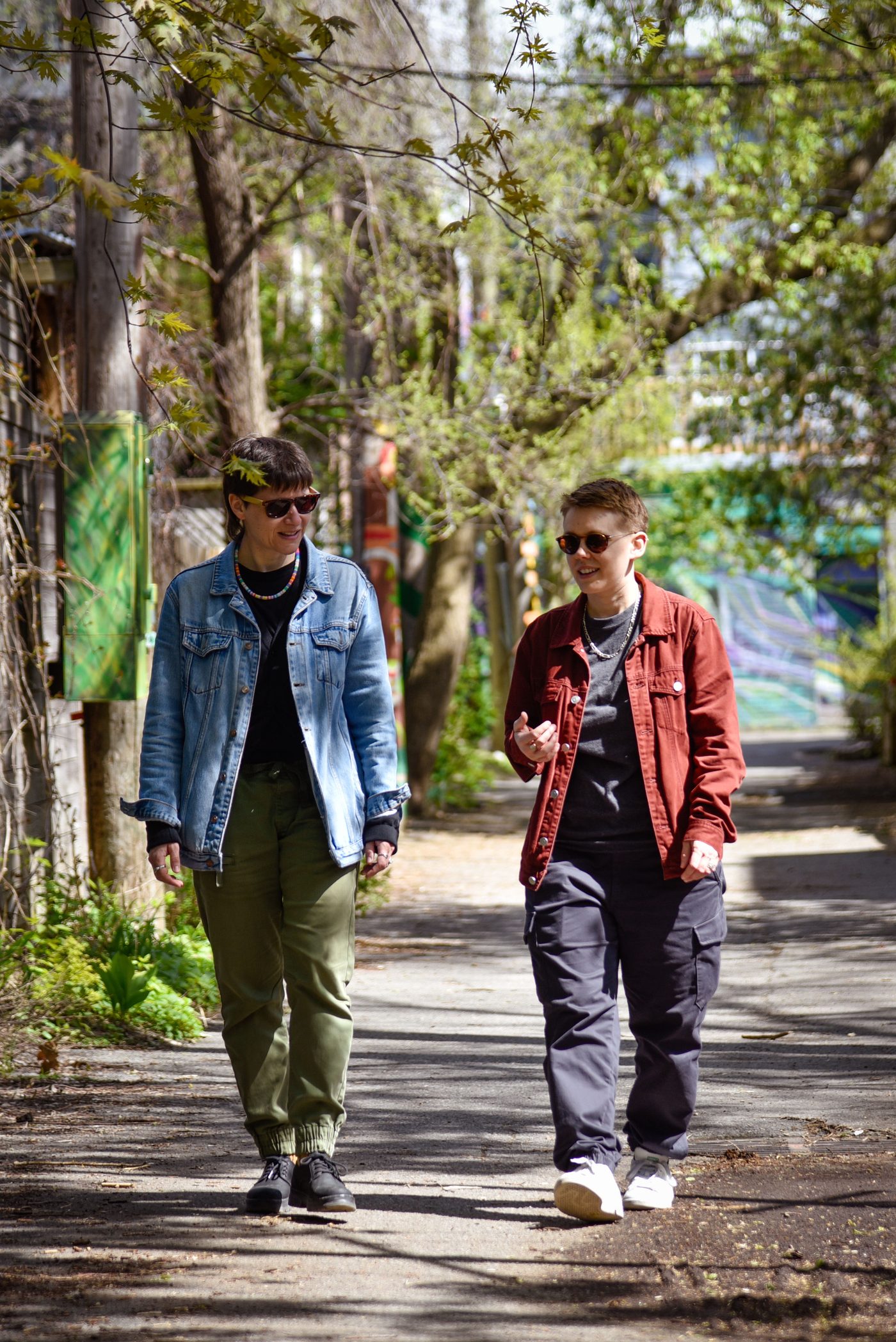 Two people walking together and talking along a tree-lined alley.